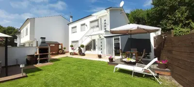 a small yard with a white house and an umbrella at PortoHouse in Portomarin
