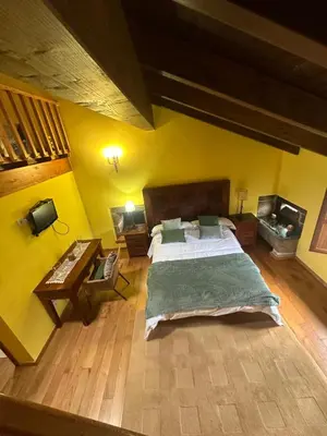 a bedroom with a large bed and yellow walls at Casa Rural Anxeliña in Boborás