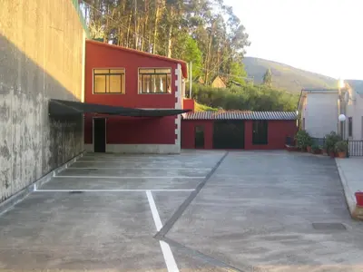 a parking lot in front of a red building at Hotel Chola in Dorna