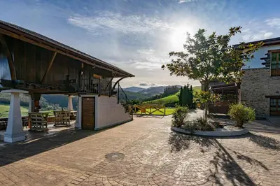 a building with a patio with a tree and mountains at Alborada del Eo in Vegadeo