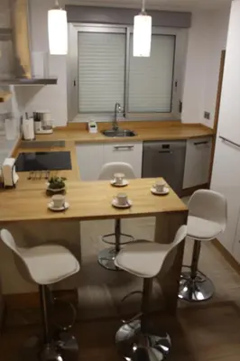 a kitchen with a wooden counter and white chairs at Rosalía de Castro, 41 - Centro - VUT-CO-01904 in Santiago de Compostela