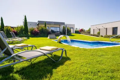 a yard with lawn chairs and a swimming pool at Hotel A Curuxa Wellness in Arzúa