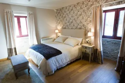 a bedroom with a bed and a chair and windows at Casa das Veigas in Santa Eulalia
