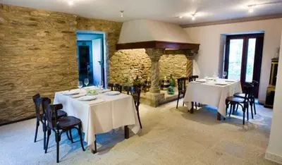 a dining room with tables and chairs and a stone wall at Casa das Veigas in Santa Eulalia