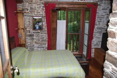 a bedroom with a bed and a stone wall at Pereje Garden in Pereje