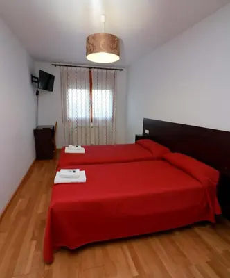 a bedroom with a red bed with a red blanket at Hostal CASASNOVAS in Silleda