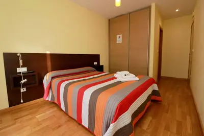 a bedroom with a bed with a colorful striped blanket at Hostal CASASNOVAS in Silleda