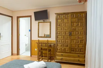a bedroom with a wooden door and a mirror at Hotel Alda Xinzo in Xinzo de Limia