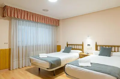 a bedroom with two beds and a window at Hotel Alda Xinzo in Xinzo de Limia