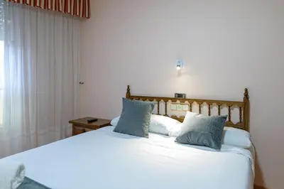 a bedroom with a large white bed with blue pillows at Hotel Alda Xinzo in Xinzo de Limia