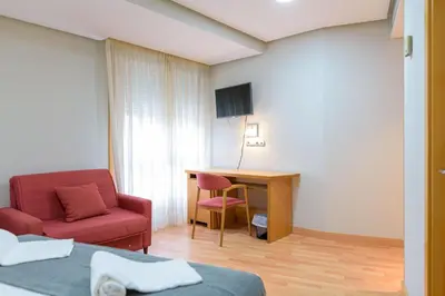 a hotel room with a red chair and a desk at Hotel Alda Xinzo in Xinzo de Limia