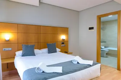 a bedroom with a large white bed and a bathroom at Hotel Alda Xinzo in Xinzo de Limia