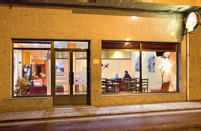 a store window with people sitting inside of it at Albergue Vía Láctea in Arzúa