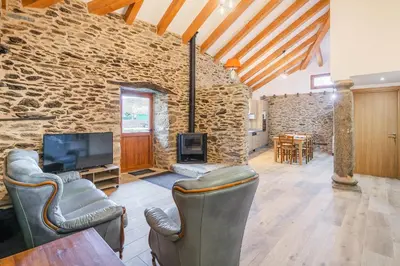 a living room with a tv and a stone wall at O Trancallo in Viana do Bolo