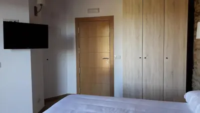 a bedroom with a bed and a closet and a television at O Trancallo in Viana do Bolo