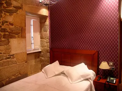a bedroom with a bed and a red wall at Hotel Casa de Caldelas in Castro Caldelas
