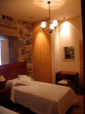 a bedroom with a bed and a stone wall at Hotel Casa de Caldelas in Castro Caldelas