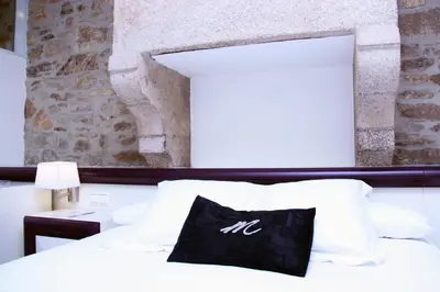 a bed with a black and white pillow on it at Hotel Montenegro Compostela in Santiago de Compostela