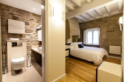 a bedroom with a bed and a stone wall at Hotel Montenegro Compostela in Santiago de Compostela
