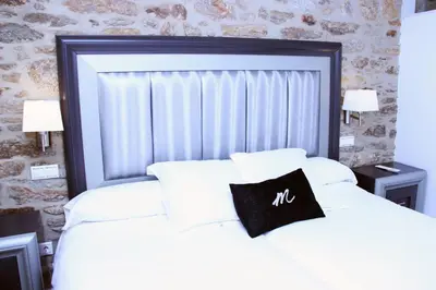 a bedroom with a white bed with a black pillow on it at Hotel Montenegro Compostela in Santiago de Compostela