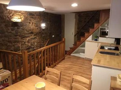 a kitchen and dining room with a stone wall at Bonita Casa en Pontedeume in Puentedeume