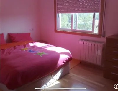 a bedroom with a bed with pink walls and a window at A Coruña al lado de la playa in Bastiagueiro