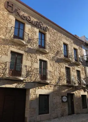 a stone building with a sign on the side of it at Hotel Roquiño in Caldas de Reis