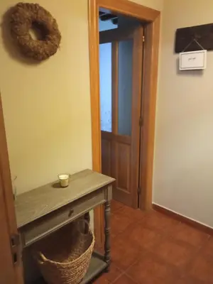 a hallway with a table and a door with a basket at Hotel Arco Navia in Navia