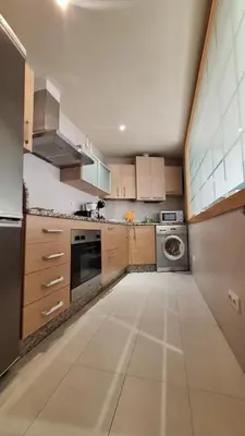 a kitchen with wooden cabinets and a washer and dryer at Dúplex Plaza Saco y Arce in Ourense