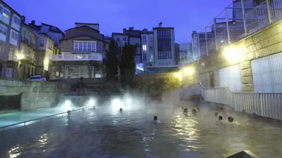 a group of people swimming in a fountain at night at Dúplex Plaza Saco y Arce in Ourense