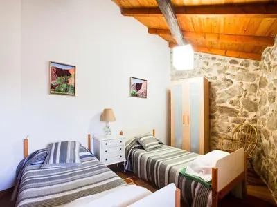 two beds in a room with a stone wall at Farmhouse in Castrotañe with Terrace in Castillón