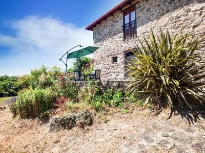 a stone building with a table and an umbrella at Farmhouse in Castrotañe with Terrace in Castillón