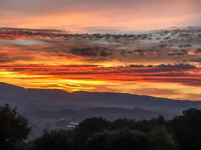 a sunset with the sun setting over the mountains at Farmhouse in Castrotañe with Terrace in Castillón