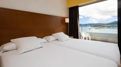 three beds in a hotel room with windows at Hotel Thalasso Cantabrico Las Sirenas 4 Superior in Viveiro