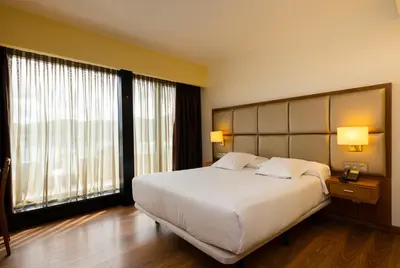 a hotel room with a bed and a large window at Hotel Thalasso Cantabrico Las Sirenas 4 Superior in Viveiro
