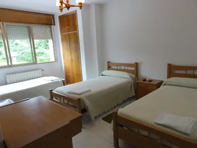 a small room with two beds and a table at Pensión Monterredondo in Meira