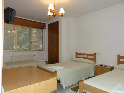 a room with two beds and a table and a window at Pensión Monterredondo in Meira