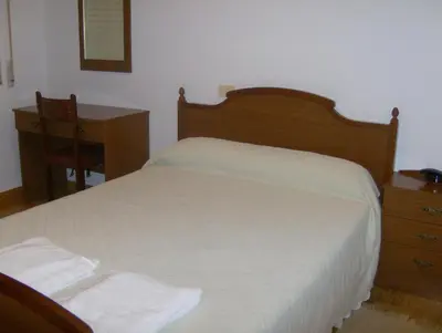a bedroom with a bed and a desk and a table and chair at Pensión Monterredondo in Meira