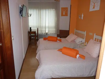 two beds in a room with orange pillows on them at Hotel España in Lugo