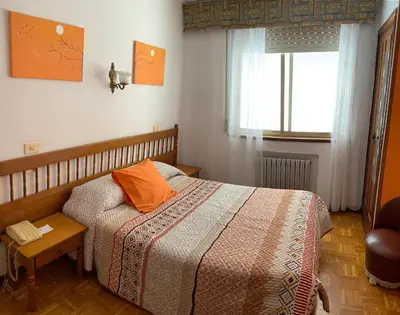 a bedroom with a bed with an orange pillow on it at Hotel España in Lugo