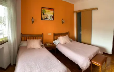 two beds in a room with orange walls at Hotel España in Lugo