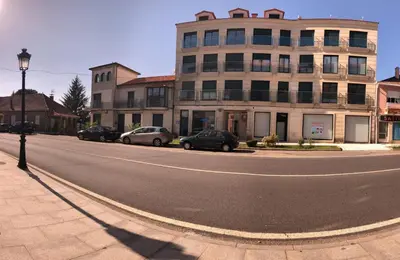 an empty street with cars parked in front of a building at Apartamentos Augusto in La Cañiza