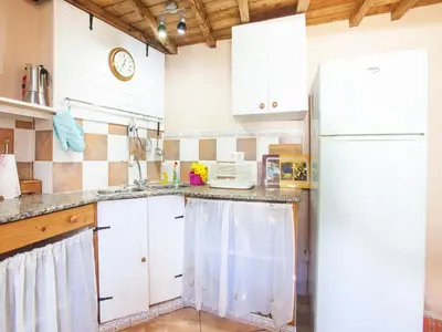 a kitchen with white cabinets and a white refrigerator at Traditional Apartment in Ribeira Sacra with Garden in Castillón