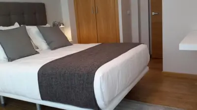 a bedroom with a large bed with white sheets at APARTAMENTOS PORTA NOVA in Lugo