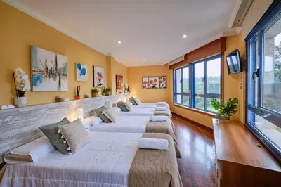 a row of beds in a room with windows at Peregrina Pensión 1 in O Pedrouzo