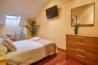 a bedroom with a bed and a dresser with a television at Peregrina Pensión 1 in O Pedrouzo