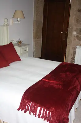 a bedroom with a white bed with a red blanket at A Casa da Meixida in Padrón