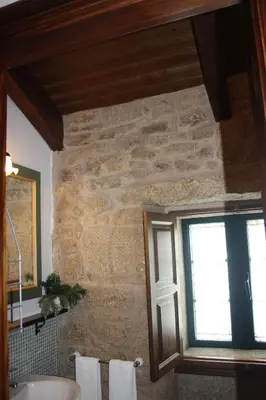 a bathroom with a stone wall and a window at A Casa da Meixida in Padrón