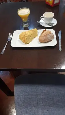 a table with a plate with bread and a glass of orange juice at Albergue A Ponte Ribadeo in Ribadeo