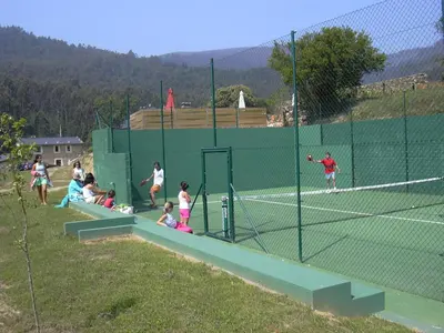 a group of people playing tennis on a tennis court at Areal in Viveiro